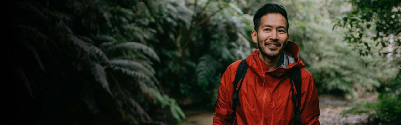 Man hiking in park surrounded by trees and plants.