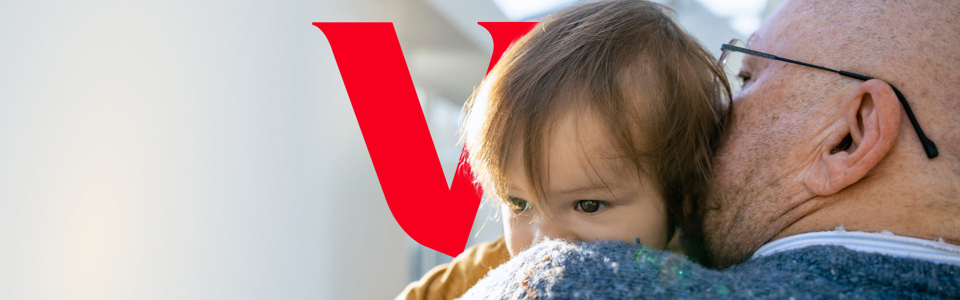 An older man wearing glasses carries a child.