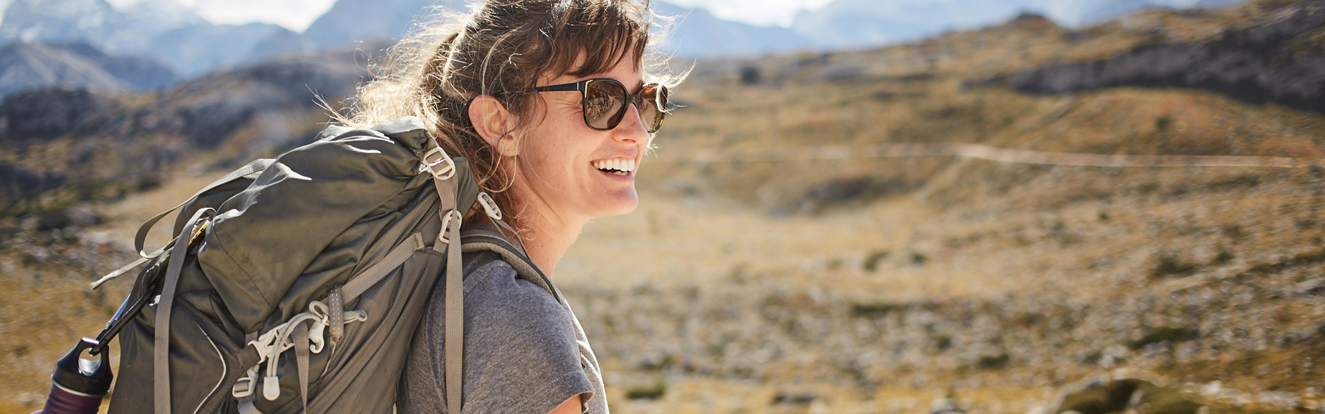 A woman walking outside hiking on a mountain and smiling