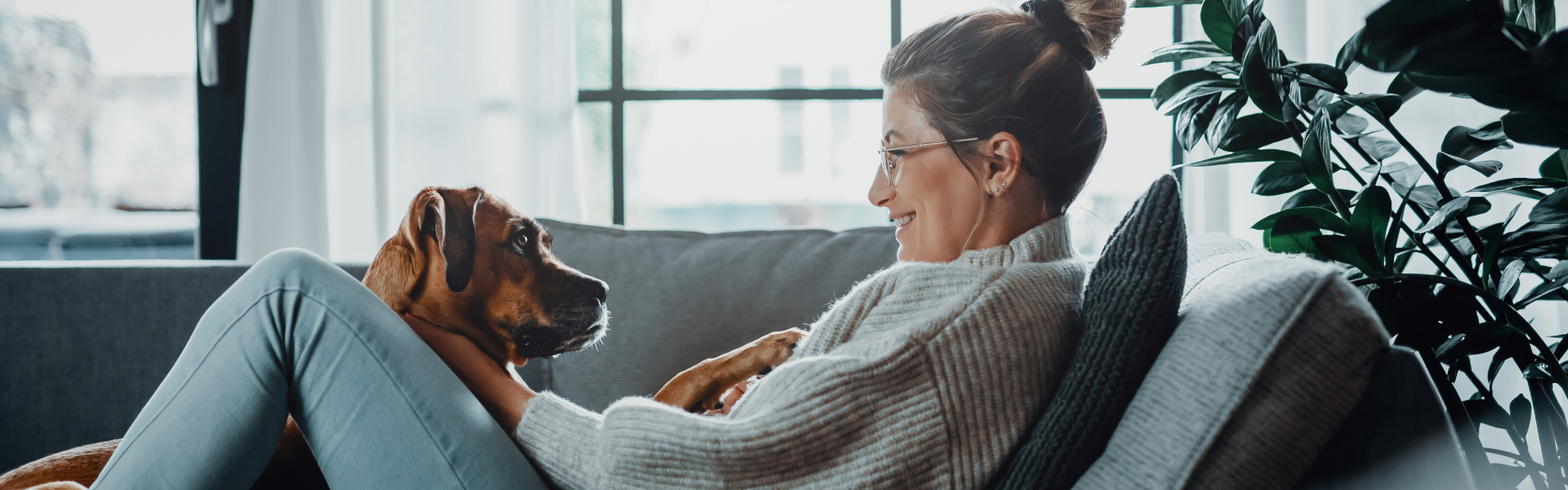 A woman is smiling at her dog laying in her lap.