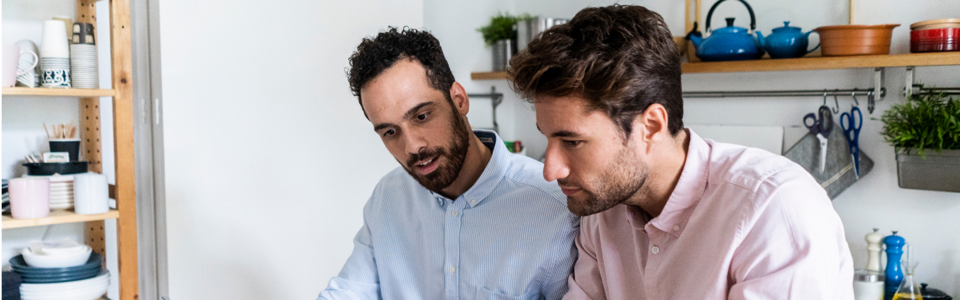 Two young men are looking down at something out of the frame.