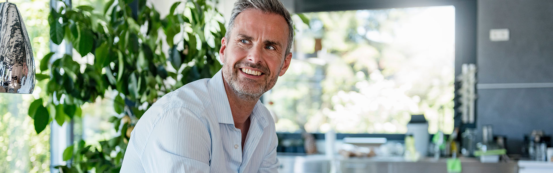 A man sitting at a kitchen counter and smiling.