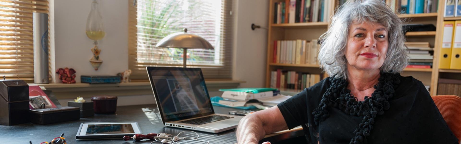 A woman is sitting in front of an open laptop on a desk.