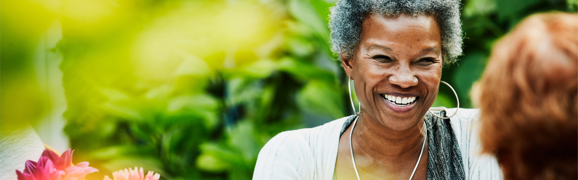 Two women in garden, laughing and enjoying each other's company.