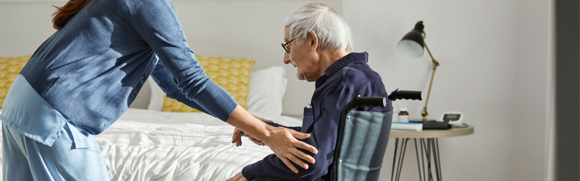 Care provider assists patient into his wheelchair.