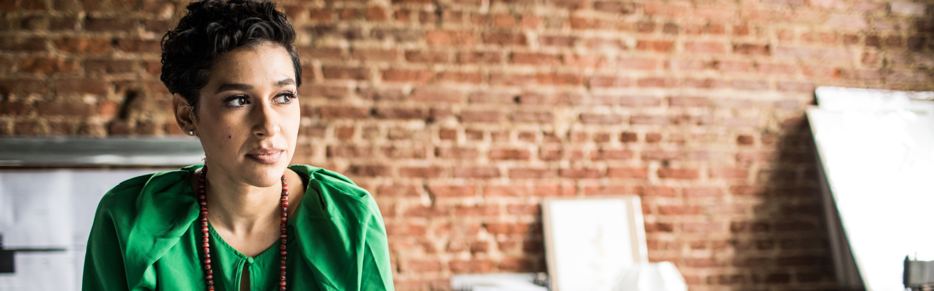 A woman is seated and looking off to her side at something out of the frame.