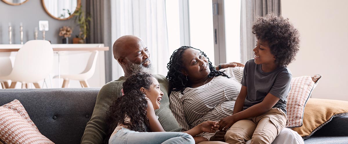 A family of four sitting on the sofa, enjoying a laugh together.